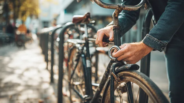 Man's hands securing his bike to a city rack with a U-lock, a picture of collateral in secured sunset loans